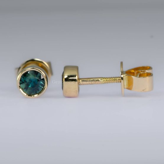 Close-up view of Australian Teal Sapphire Bezel Stud Earrings in 18K Yellow Gold, showing the side profile and intricate bezel setting details.