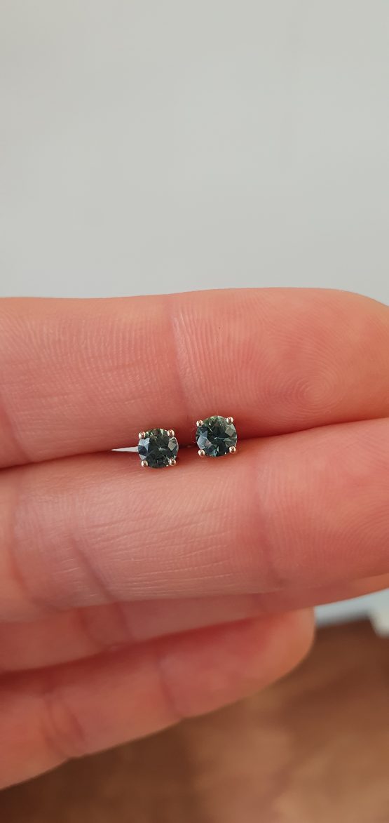 view on hand of Australian Teal Sapphire Stud Earrings in 18K White Gold – 0.58ct Round Cut - 1982779