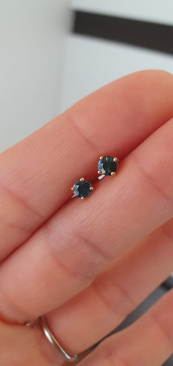 view on hand of Australian Teal Sapphire Stud Earrings in 18K Yellow Gold – 0.53ct Round Cut - 1982780