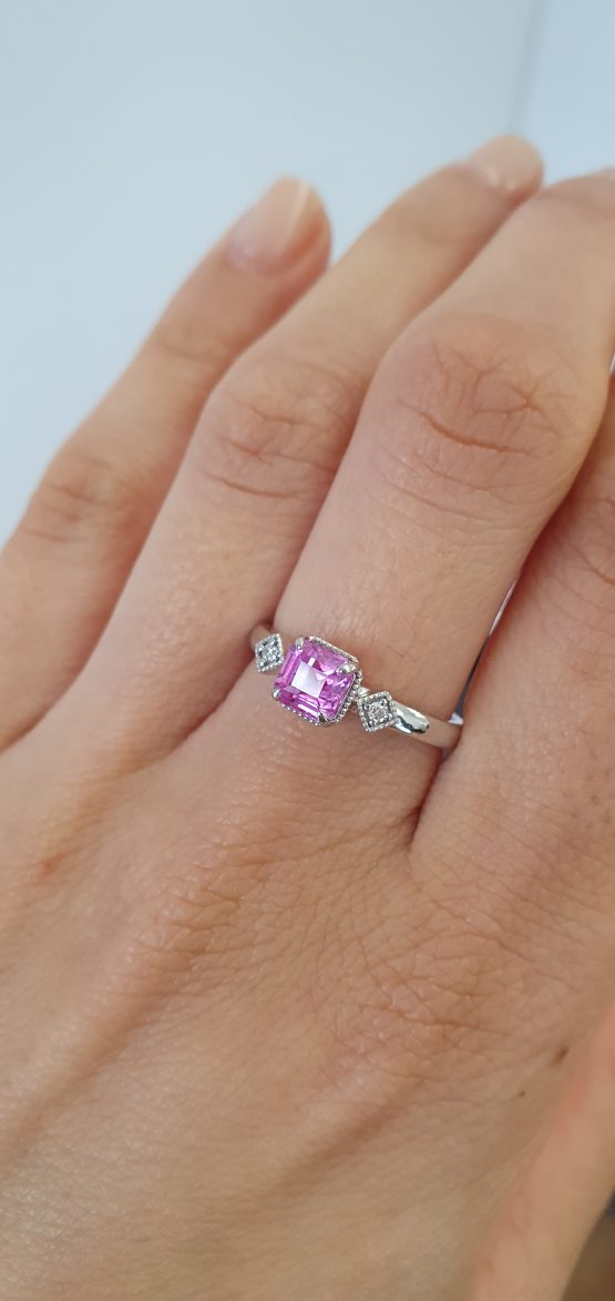 photo on hand of 1.05ct Natural Unheated Emerald Cut Pink Sapphire Ring in Platinum 950 with Diamond Accents and Filigree Detail