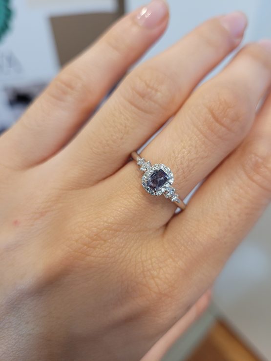 indoor light photo on hand of Platinum Alexandrite Ring with Diamond Halo and Side Accents